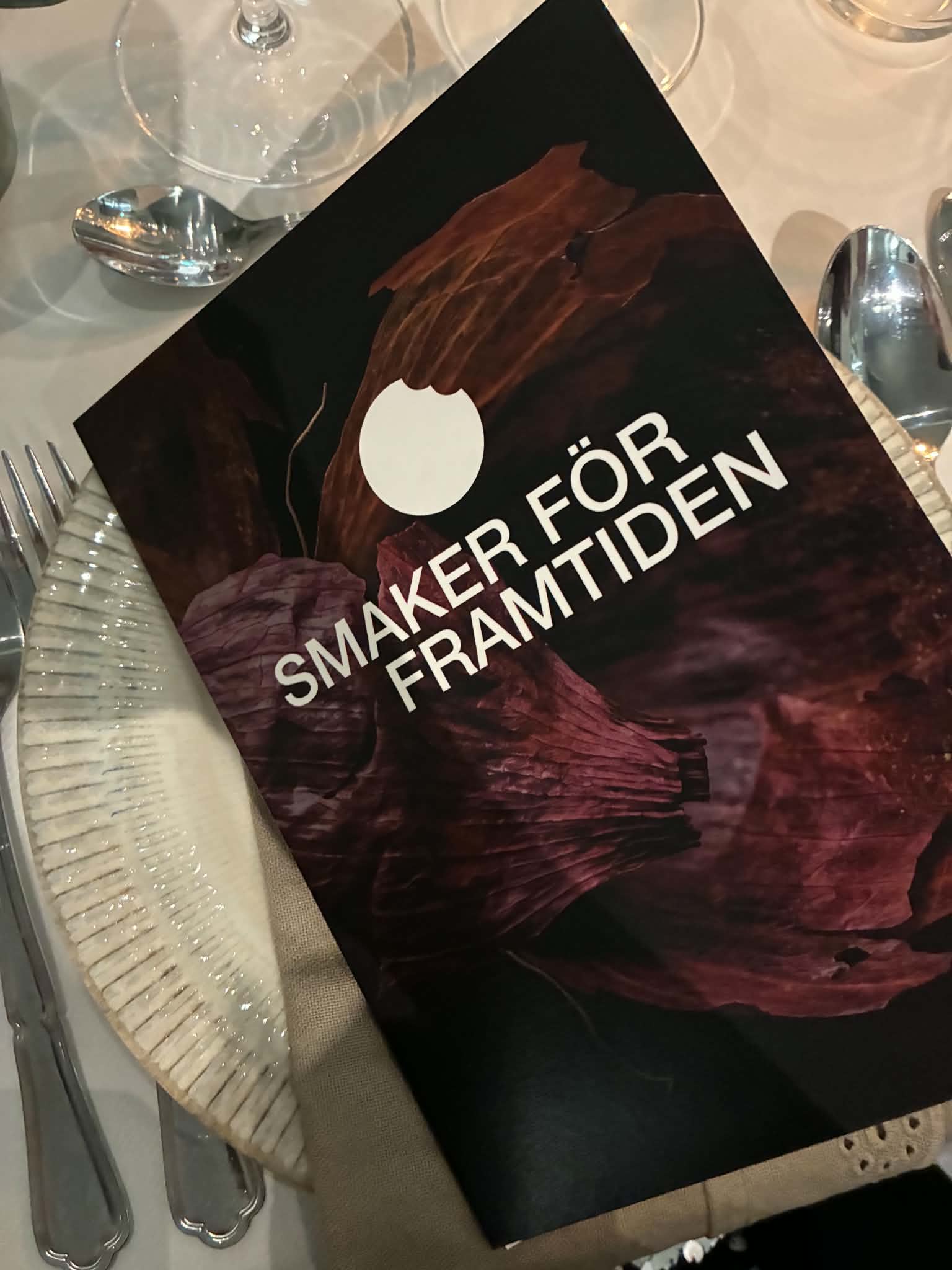 Programhäftet för Smaker för framtiden på det dukade middagsbordet.